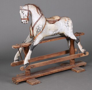 In the manner of Ayres, a dappled grey painted rocking horse, raised on a pine cruciform base 90cm h x 107cm w x 38cm d 