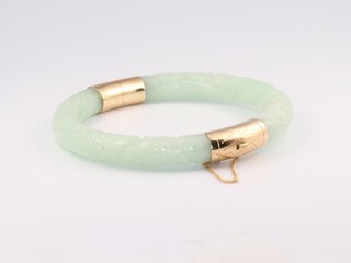 A gold mounted pale carved jade bangle, the interior diameter 5cm 