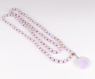 A pale purple jade circular pendant 5cm with an 18ct white gold and platinum mount set with 3 diamonds, approx. 0.11ct suspended on a ditto purple jade bead necklace, each bead 10mm diameter, 122cm long, 