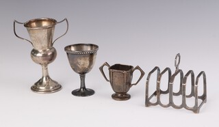 A silver 5 bar toast rack Birmingham 1962, 2 small trophy cups and an egg cup 164 grams
