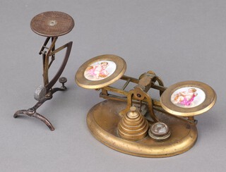J Vincent Junior of Weymouth, a pair of Victorian gilt metal postage scales with porcelain plaques  decorated cherubs to the pans, raised on an oval metal base with 6 weights and 2 non matching weights 5cm h x 18cm w x 9cm d, (left hand porcelain panel is loose) together with a set of Ges.Gesch postal scales 