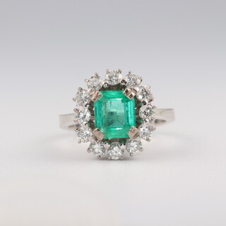 An 18ct white gold emerald and diamond cluster ring, the emerald cut centre stone approx. 1.5ct, the brilliant cut diamonds 0.4ct, 5.1 grams, size G 1/2