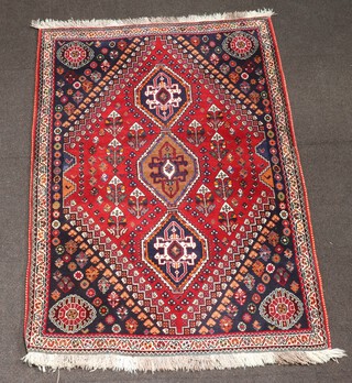 A red and tan ground North Persian rug with 3 diamond shaped medallions to the centre within a diamond medallion 164cm x 115cm 