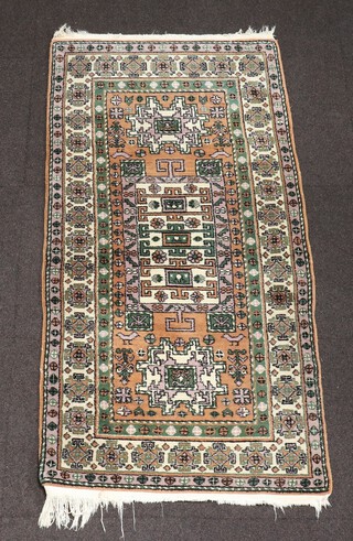 A yellow and green ground Afghan rug with rectangular medallion to the centre flanked by square medallions 150cm x 76cm 
