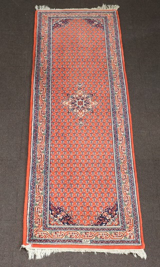 An orange and blue ground North Persian runner with medallion to the centre and hooked overall design, signed to the edge 254cm x 83cm 