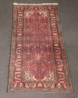A red and green ground Persian rug with central medallion in a multi row border 209cm x 104cm 
