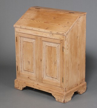 A 19th Century pine bureau, the fall front revealing a plain interior, the base fitted cupboard enclosed by carved panelled doors, raised on bracket feet 92cm h x 71cm w x 39cm d 