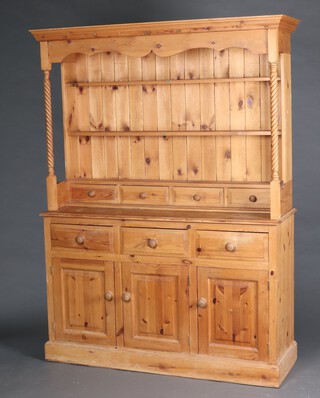A Victorian style pine dresser with moulded cornice, fitted 3 shelves above 4 spice drawers and spiral turned columns to the sides, the base fitted 3 drawers above triple cupboards, raised on a platform base 193cm h x 129cm w x 54cm d 