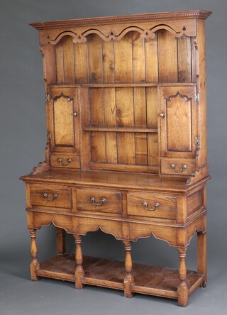 A Georgian style oak dresser, the raised back fitted cupboards and shelves, the base fitted 3 drawers above cupboard, raised on turned supports 200cm h x 134cm w x 50cm d 