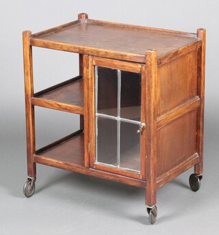 A 1930's oak 3 tier tea trolley fitted a cabinet enclosed by lead glazed panelled doors 71cm h x 61cm w x 43cm d 
