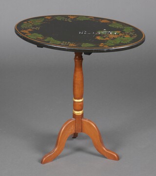 An oval black and gilt painted snap top wine table with grape decoration, raised on a pillar and tripod base 56cm h x 56cm x 41cm 