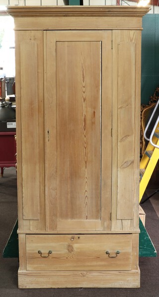 A Victorian stripped pine wardrobe with moulded cornice enclosed by a panelled door, the base fitted a drawer on a platform base 182cm h x 95cm w x 40cm d (in one piece) 