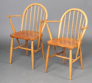 A pair of mid-Century Ercol style beech and elm comb back chairs with solid seats, raised on turned supports with H framed stretcher, the back with utility mark and 290 F182 84cm h x 60cm w x 40cm d 