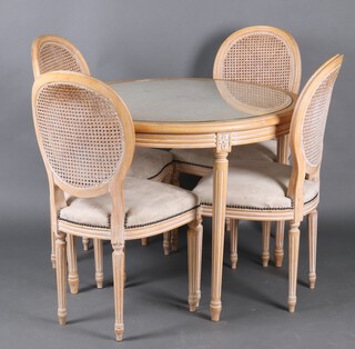 An Empire style bleached oak dining suite comprising circular dining table with woven cane top, raised on turned and fluted supports 76cm x 99cm diam. together with 4 beech framed dining chairs with double cane backs, seats upholstered in suede 