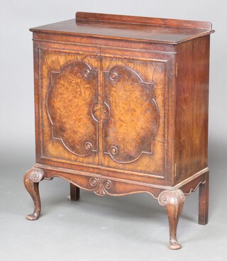 A 1930's Queen Anne style walnut cabinet with raised back, fitted shelves enclosed by panelled doors, raised on cabriole supports 102cm h x 82cm w x 41cm d 