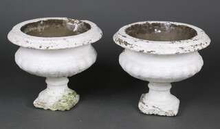 A pair of white painted circular garden urns with reeded bodies raised on square bases 42cm h x 46cm diam. 