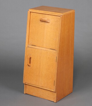 A G-Plan style light oak bedside cabinet with fall front above panelled door 85cm h x 38cm w x 31cm d