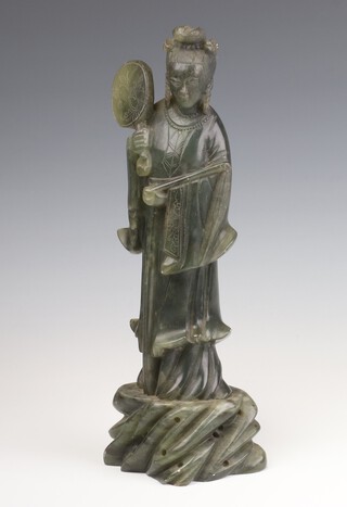 A Chinese soapstone figure of a standing lady holding a fan in her right hand standing on a rocky base 30cm 