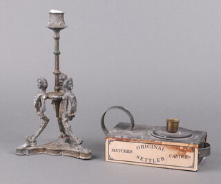A Victorian base metal candlestick supported by 3 female masks raised on a tripod base (cracked) 28cm x 14cm together with a novelty pressed metal chamber stick in the form of a match box marked Original Settler Matches and Candles  5cm x 17cm x 10cm 