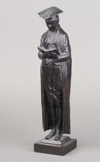 A 19th Century iron figure of a standing school master wearing a gown with mortar board and book, raised on a square base 29cm 