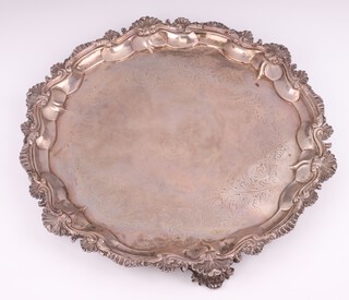 A Victorian silver salver with shell and scroll rim and engraved scrolls enclosing an armorial on scrolled feet London 1873, maker Daniel and Charles Houle, 36cm, 1294 grams 