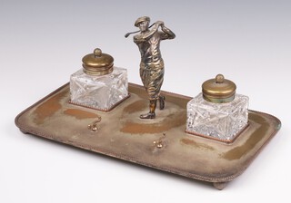 A silver plated ink stand with brass mounted square ink wells, pen rest and figure of a golfer, raised on ball feet 34cm, Made by Merchants Ltd. 