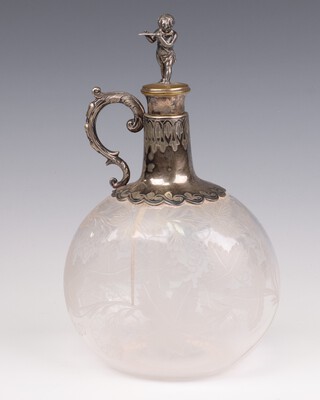 An Edwardian engraved glass decanter and stopper with plated mounts decorated with vinous decoration, the stopper surmounted by a figure of a child playing a flute  23cm 