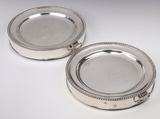 A pair of silver plated twin handled plate warmers and plates with gadrooned rims 25cm  
