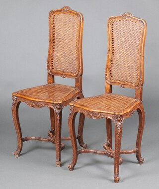 A pair of Italian carved walnut hall chairs with woven cane seats and backs, raised on French cabriole supports with X framed stretchers 97cm h x 40cm w x 34cm d (seats 16cm x 23cm) 