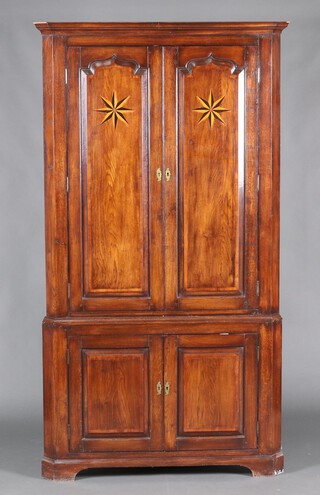 A Georgian inlaid oak double corner cabinet with moulded cornice, fitted shelves enclosed by inlaid star panelled doors, the base enclosed by a panelled door, raised on bracket feet 204cm h x 78cm w x 112cm 