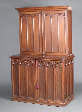 A Victorian carved oak Gothic style cabinet on cabinet with moulded cornice, the interior fitted pigeon holes enclosed by arched panelled doors, the base fitted a shelf enclosed by arched panelled doors 194cm h x 122cm w x 62cm d 