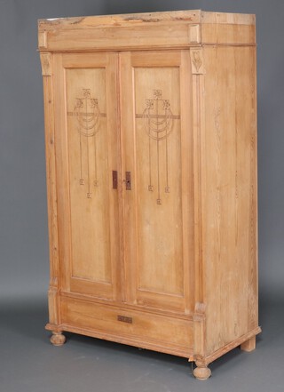 An Art Nouveau Continental stripped pine wardrobe enclosed by panelled doors, the base fitted a dummy drawer 173cm h x 105cm w x 57cm d (cornice loose and in 3 pieces)