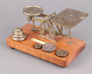 A set of Edwardian brass postage scales on a wooden plinth with weights 