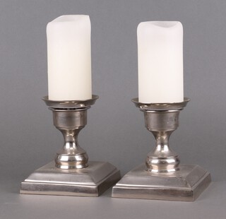 A pair of polished metal urn shaped candle holders with square bases 14cm 