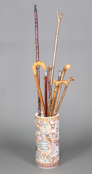 A Chinese style cylindrical pottery stick stand containing a collection of walking sticks 