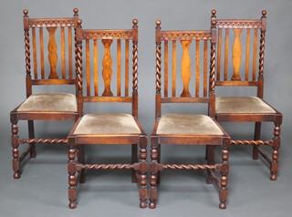 A set of 4 1930's oak stick and bar back dining chairs with carved bar backs and upholstered drop in seats, raised on spiral turned supports 