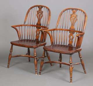 A pair of 20th Century elm comb back Windsor carver chairs with solid seats and crinoline stretchers, raised on turned supports 104cm h x 53cm w x 42cm (seats 38cm x 40cm) 
