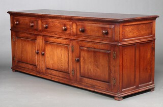 An 18th Century style solid oak dresser base fitted 3 drawers above a triple cupboard, raised on a platform base 80cm h x 199cm w x 61cm d 