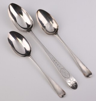 A George III silver serving spoon with engraved decoration and armorial, Dublin 1766 and 2 Georgian table spoons, rubbed marks, 256 grams 