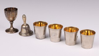 A German 800 standard silver egg cup, a hand bell and 4 tots 