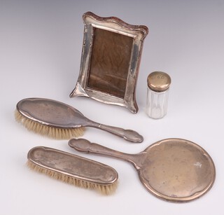A silver backed 3 piece dressing table set with hand mirror, clothes brush and hair brush, Birmingham 1949, a silver photograph frame 19cm Birmingham 1916 and a silver mounted toilet jar Birmingham 1907 