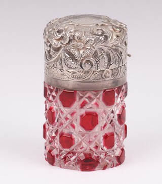A Victorian silver mounted cylindrical cut glass red and clear glass scent bottle with repousse floral lid and monogram Birmingham 1876, 6cm 