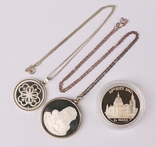 A 1977 Christmas silver medallion, a commemorative crown, 1 other and 2 silver necklaces 93 grams 
