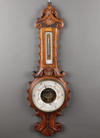 A Victorian aneroid barometer and thermometer contained in a carved oak wheel case with replacement thermometer 83cm h x 27cm 