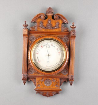 A Victorian aneroid barometer with circular silvered dial, contained in a carved walnut case with broken pediments 49cm x 27cm 