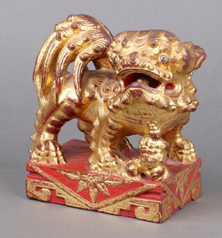 A Chinese carved soapstone figure of a Shi Shi with a loose ball pearl in his mouth with gilt and red decoration 16cm 