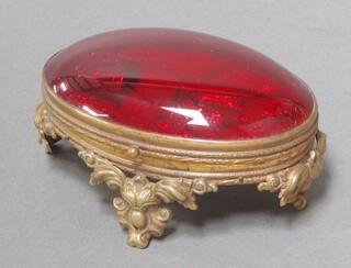 An Edwardian gilt metal and steel sewing set comprising pair of scissors, needle, embossed needle case and thimble, contained in an oval pierced gilt metal and red plastic domed case 4cm h x 10cm w x 7cm d 