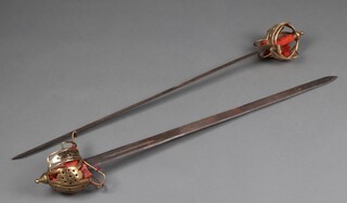 A pair of Victorian reproduction Scottish basket hilt swords with 91cm steel blades and gilt basket hilts 