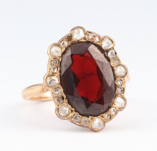 An 18ct yellow gold garnet and diamond cluster ring, the centre garnet 3cts, the brilliant cut diamonds 0.25ct, size J, 3.4 grams