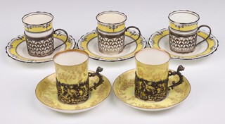 A Royal Crown Staffordshire yellow and gilt coffee can with silver plated frame, a similar Staffordshire egg shell coffee can (a/f) and 2 matching saucers with silver holders Birmingham 1904, together with 4 Aynsley black and gilt banded coffee cans (2 a/f, 1 has a chip) with small plates and silver holders Birmingham 1923 (gross silver weight 144 grams)